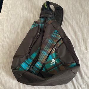 Adidas crossbody dark brown backpack w/ a bluish/greenish plaid pattern